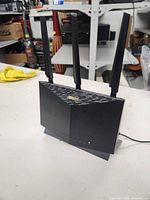 Front view showing three tall antennas and LED indicator lights on the router.