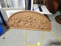 Front view of the semi-circular cherub relief wall hanging artwork showing detailed cherubs in sculptural relief.