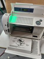 Open Cricut Pro Craft Cutter showing keyboard, slot for cutting mat, and front panel with instructions.