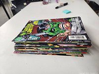 Stack of 25 Green Lantern comic books lying flat on a table showing comic cover spines and edges.