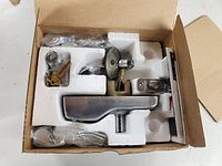 Photo showing the keypad lockset components neatly arranged in original packaging with foam inserts: exterior keypad lever, interior lever, latch, strike plate, two keys, and other parts.