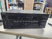 Front view of the Sony multichannel AV receiver showing the power on display, input buttons, and volume control.