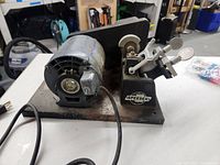 Side front view of Speedex Key Cutting Machine with visible motor, cutting wheel, and key clamp on a metal base.