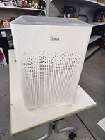 Front view of the white Winix AM90 air purifier showing perforated front panel and brand logo.
