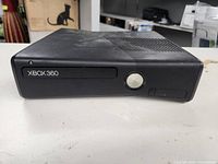 Front view of black Xbox 360 Elite gaming console showing disc drive and power button.