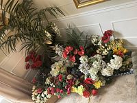 View of various artificial flowers arranged on the floor with some in pots, showing multiple flower colors and types.