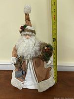 Santa figurine approximately 17 inches tall wearing brown coat with white fur trim, holding watering can and decorated sack