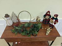 Top view of Christmas decorations on wooden table with snowman, carolers, reindeer, wreath, and ornaments