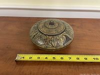 Round decorative lidded lunch box with geometric and bird motifs, about 9 inches across, closed with lid on top