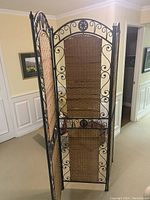 Side view showing the thickness and hinge connection of the panels and detailed metal scrollwork and woven wicker insert in the panel.