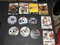 12 PlayStation 2 game discs and cases including God of War, NBA 2K5, Crazy Taxi, Dangerous Hunts, and Madden games.