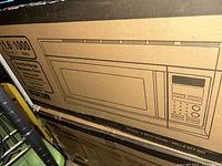 Box of 1.6 cu. ft. Over the Range Microwave model MC0165UW with a simple line drawing of the microwave and control panel.