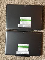 Rear view of two Magnus III tablets showing black casing with camera and support sticker on each