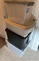 Stack of four plastic storage containers of various colors and sizes with lids.