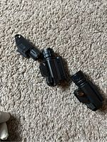 Three black beam and light attachments lying on carpet. Components are black plastic and separated with visible missing screws.