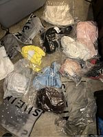 Top view of assorted brand new women's clothing items individually packaged in plastic, size XL.