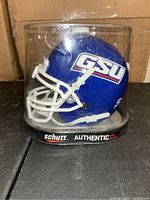 Blue mini football helmet with white facemask and 'GSU' logo in clear Schutt Authentic display case.