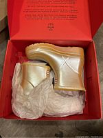 Pair of gold Hunter rain boots in original red Hunter box with tissue wrapping.