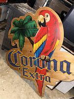 Photo of a large wood sign depicting Corona Extra text with a colorful parrot and palm tree graphics.