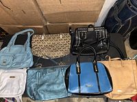 Seven assorted purses including Michael Kors, Anne Klein, Rosetti, and Carlos, displayed close together on a flat surface with some handles visible.