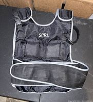 Black Spri weight vest on table showing front side with adjustable straps and buckles