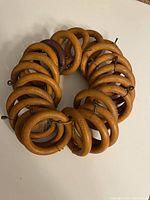 Set of 22 antique wood curtain rings arranged in a circle on a light-colored surface, showing wood grain and metal hooks attached for curtain hanging.