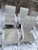 Photo of three alloy frame lawn chairs and one matching ottoman, shows outdoor snowy setting with visible dirt on fabric surfaces.
