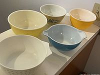 Five Pyrex mixing bowls arranged on countertop, showing color and shape variety
