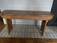 Front view of the antique pine bench showing the rectangular top, legs, and aged wood with natural wear and patina.