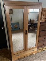 Front view of Mid-Century Modern style wooden wardrobe with two mirrored doors and decorative handles.
