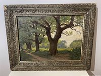 Front view of oil painting showing landscape of oak trees and ornate decorated frame.