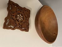 Photo of the carved wood trivet and wooden bowl side by side showing textures and designs.