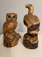 Front view of wood carved owl and eagle on a neutral background, showing details of carving and natural wood grain