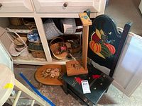 Photo showing hand painted stools, assembled book rack, and multiple woven baskets arranged on floor and shelf