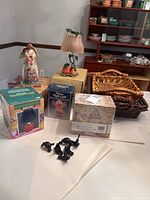 Full lot photograph showing Jim Shore angel figurine, votive candle lamp, apple lamp, mouse night light, storage box, wicker baskets, and cast metal bird drawer pulls