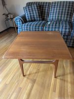Front view of teak coffee table with visible scratches on top surface, showcasing Mid-Century Modern design and wood grain.