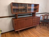 Full frontal view of the teak hutch showing upper and lower sections, sliding glass doors and drawers.