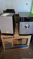 Overall view of Sony micro Hi-Fi system, speakers, and remote on top of original box