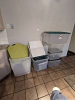 Full view of storage bins stacked and nested, with some green lids and a white milk crate.