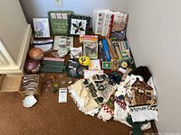 Full overview of all items including towels, cookbooks, pot holders, novelty items, and small kitchen accessories arranged on floor.