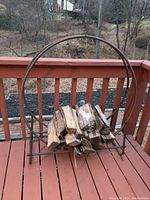 Metal wood ring filled with firewood on a wooden deck outdoors