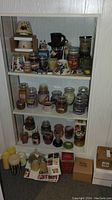 Shelves holding multiple glass jar candles, candle warmers, decorative candle items, and matchboxes arranged on and in front of shelves.