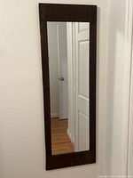 Front view of the full length mirror showing the dark wood frame and clear reflection.