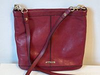 Front view of the Rebecca Minkoff wine coloured leather handbag showing brass hardware and shoulder strap arrangement.