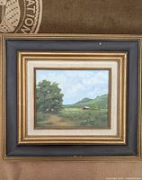 Full view of the framed oil painting showing the layered frame and landscape artwork