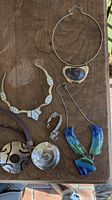 Top-down view of five necklaces and one bracelet on wooden surface showing all jewelry pieces distinctly.