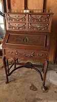 Full view of antique wooden secretary desk showing carved wood details and overall structure.