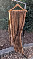 Vintage mink fur stole hanging on a wooden hanger, showing long fur and length.