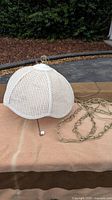 White rattan woven hanging lamp on table, with brass chain and pull cord.