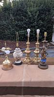 Full view of all six vintage lamp bases displayed on a table outdoors, showcasing variety in materials and designs